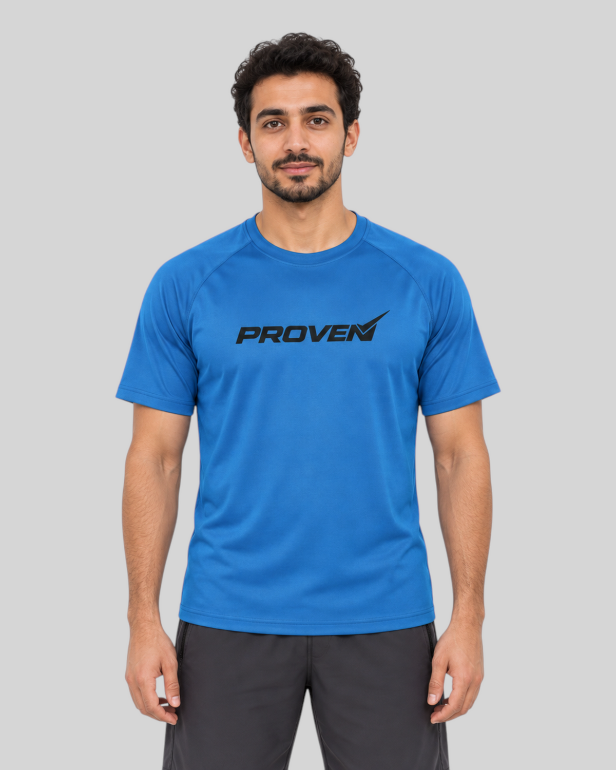 Male model wearing a goblet blue proven sport wear performance t-shirt with a black logo in a studio setting